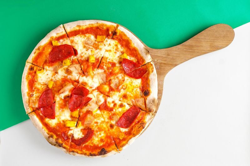 Garden fresh salad bowl served alongside round table pizza
